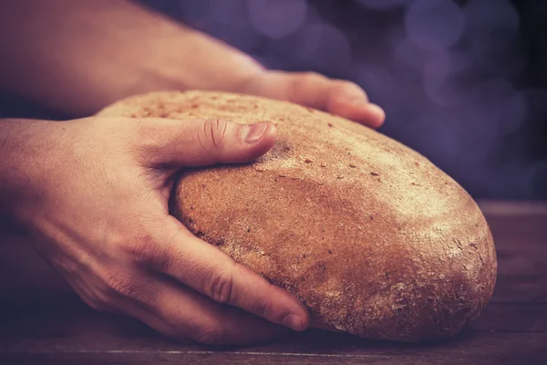 Baker's hands with a bread. — Stock Photo, Image