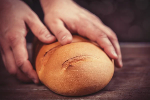 Baker's hands with a bread. — Stock Photo, Image