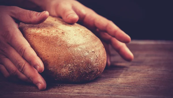 Baker's hands with a bread. — Stock Photo, Image