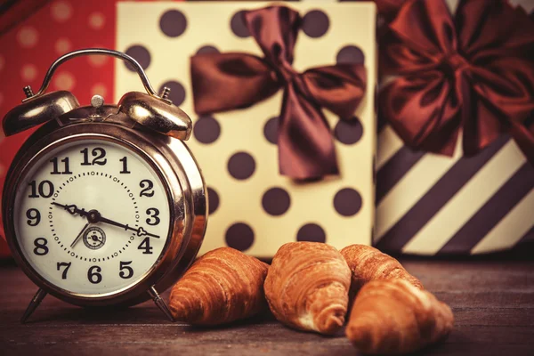 Retro väckarklocka med croissant på ett bord. — Stockfoto