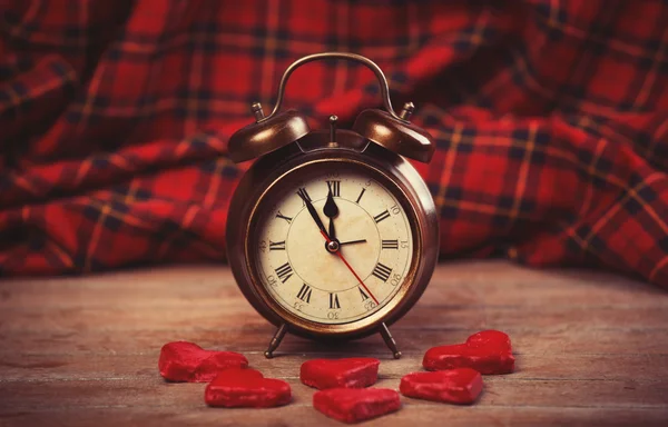 Reloj despertador retro con galleta en una mesa — Foto de Stock