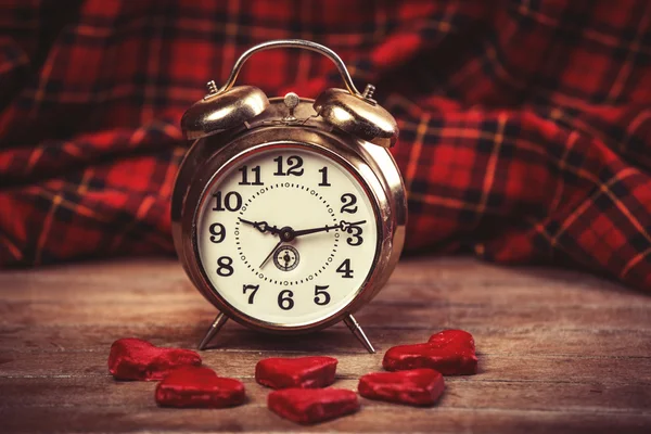 Reloj despertador retro con galleta en una mesa — Foto de Stock