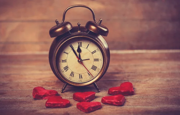 Retro alarm clock with cookie on a table — Stock Photo, Image