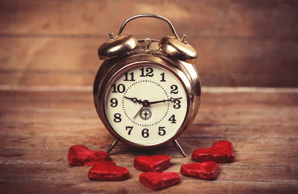 Retro alarm clock with cookie on a table — Stock Photo, Image