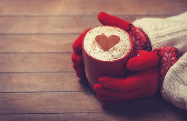 Mains dans les mitaines tenant une tasse de café chaud — Photo