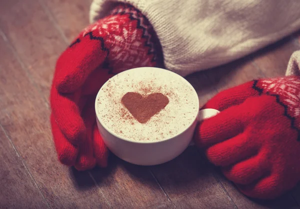 Mains dans les mitaines tenant une tasse de café chaud — Photo