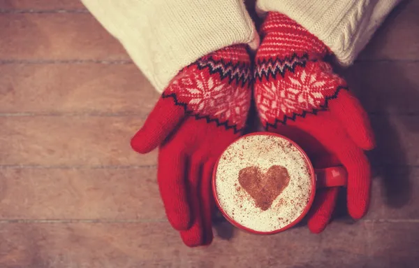 Hands in mittens holding hot cup of coffee — Stock Photo, Image