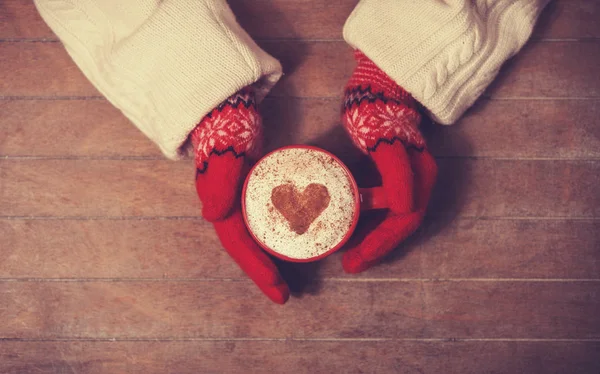 Hands in mittens holding hot cup of coffee — Stock Photo, Image