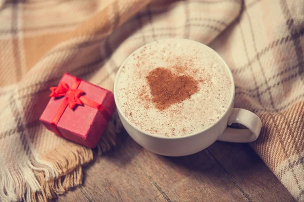 Cup with coffee and shape of the cacao heart on it and scarf — Stock Photo, Image