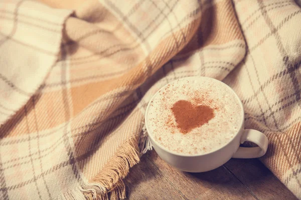 Cup with coffee and shape of the cacao heart on it and scarf — Stock Photo, Image