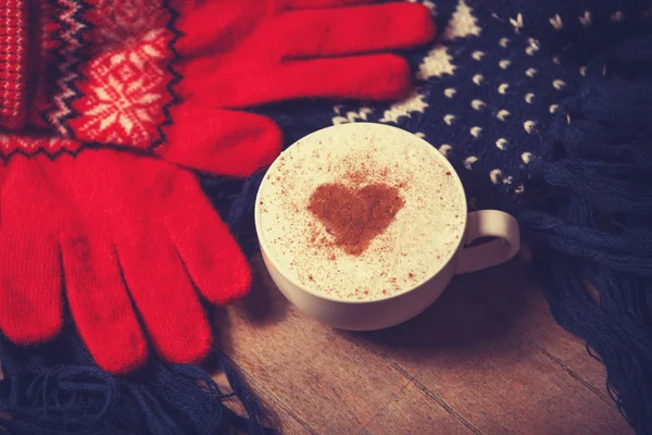 Cup with coffee and shape of the cacao heart on it and scarf. — Stock Photo, Image