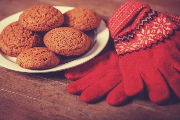 Luvas vermelhas e biscoito na mesa de madeira . — Fotografia de Stock