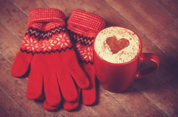 Handschuhe und Tasse mit Kaffee und der Form des Kakaoherzens darauf. — Stockfoto