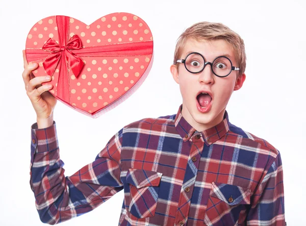 Nerd ragazzo adolescente con regalo a forma di cuore rosso . — Foto Stock