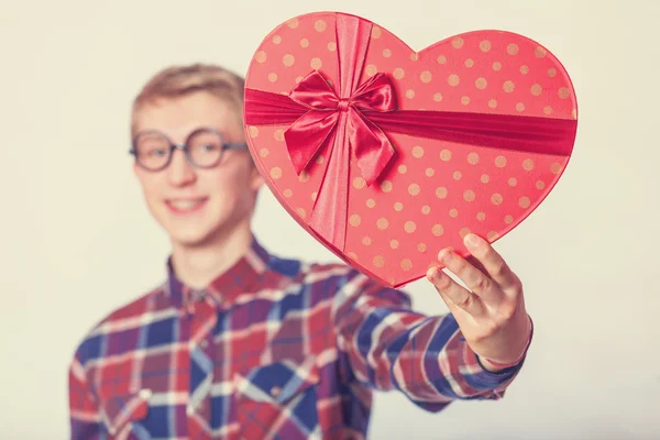 Nerd adolescente chico con rojo corazón forma regalo . —  Fotos de Stock