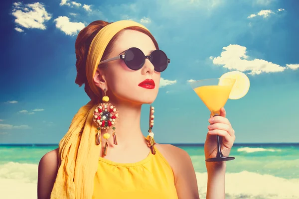 Mooie roodharige vrouwen met cocktail op het strand. — Stockfoto