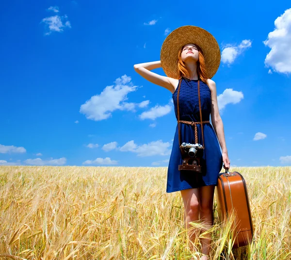 Pelirroja con maleta en campo de trigo de primavera . — Foto de Stock