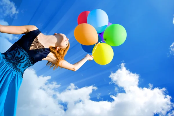 Redhead girl with colour balloons at blue sky background. — Stock Photo, Image