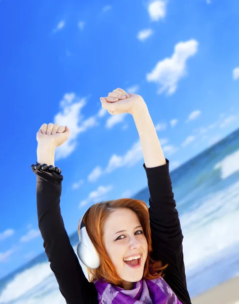 Portrait de fille aux cheveux roux avec casque sur la plage . — Photo