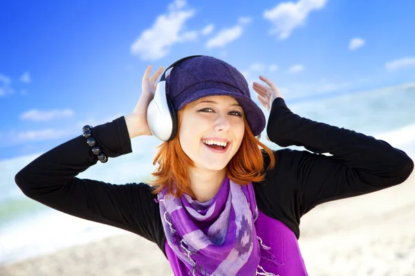 Portrait of red-haired girl with headphone on the beach. — Stock Photo, Image