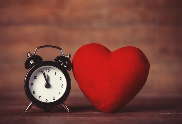 Reloj despertador retro y forma de corazón en mesa de madera . — Foto de Stock