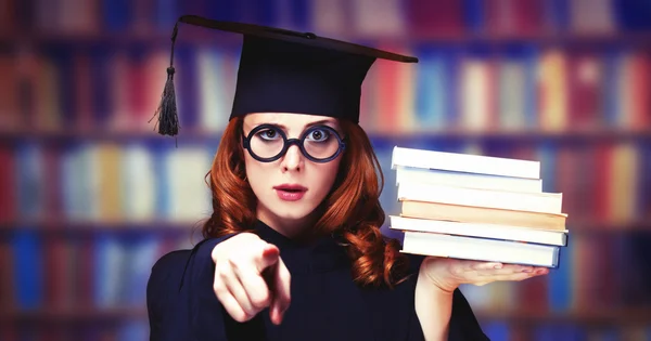 Akademik kıyafetli, kitaplarla mezun olmuş bir kız. — Stok fotoğraf