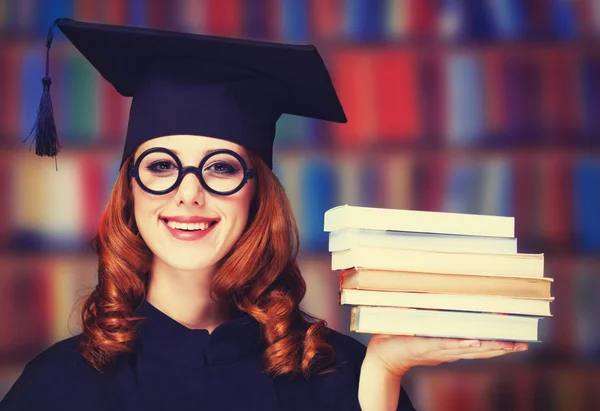 Abschlussschülerin im akademischen Kleid mit Büchern — Stockfoto