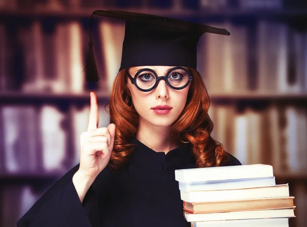 Випускниця студентка в академічній сукні з книгами — стокове фото