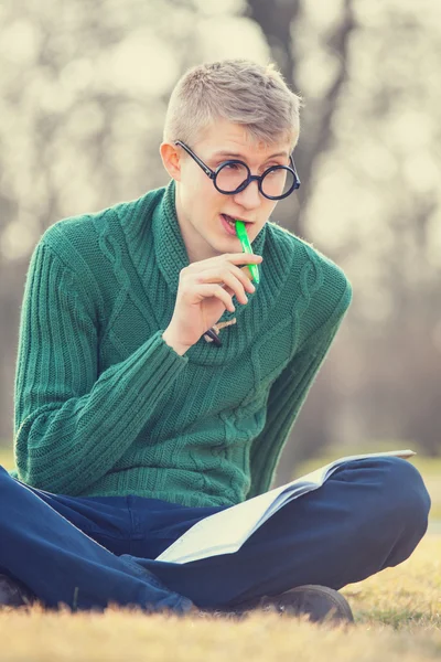 Legrační student s perem trávě — Stock fotografie