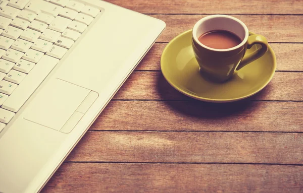 Xícara de café e laptop em uma mesa de madeira . — Fotografia de Stock