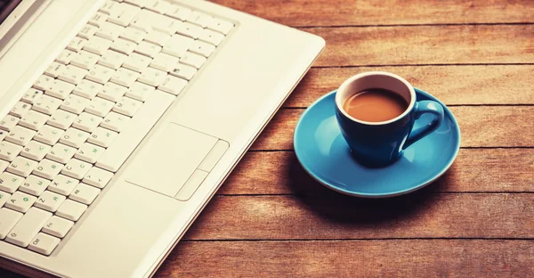 Tasse Kaffee und Laptop auf Holztisch. — Stockfoto