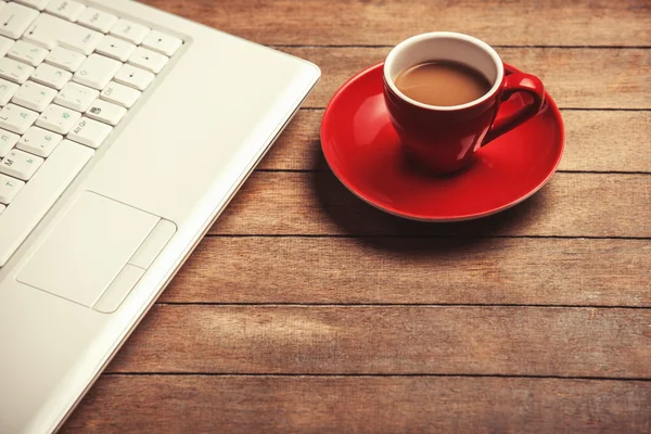 Tasse Kaffee und Laptop auf Holztisch. — Stockfoto