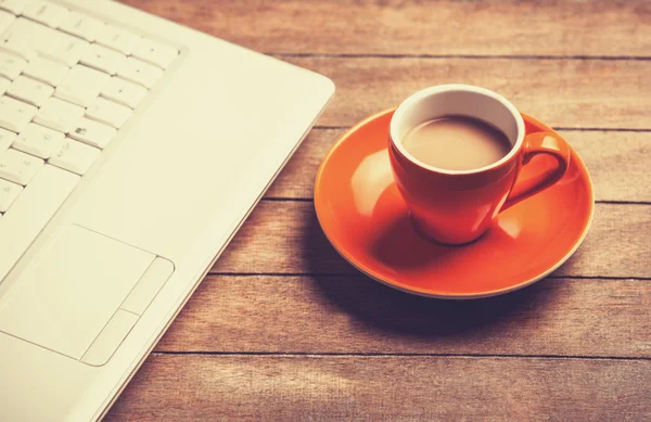 Tasse Kaffee und Laptop auf Holztisch. — Stockfoto