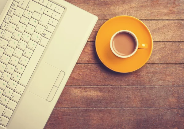 Xícara de café e laptop em uma mesa de madeira . — Fotografia de Stock