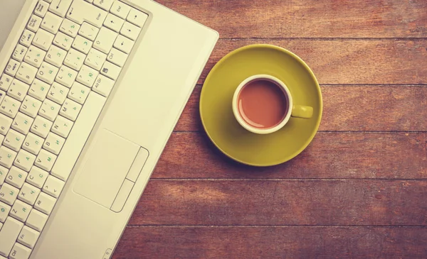 Kopp kaffe och laptop på ett träbord. — Stockfoto