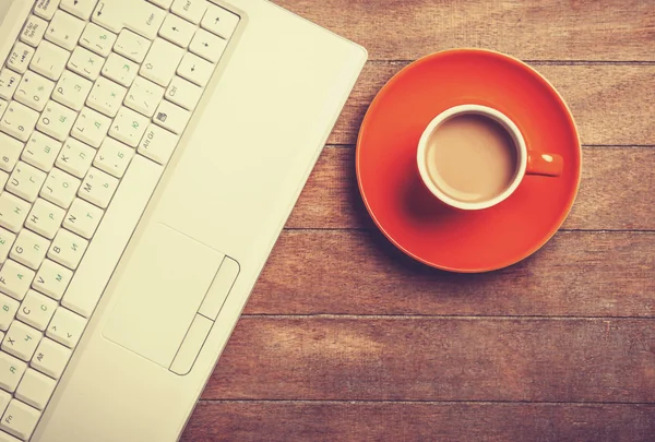 Tasse Kaffee und Laptop auf Holztisch. — Stockfoto