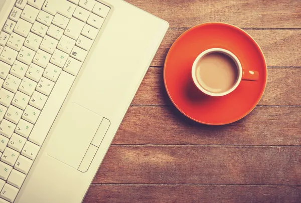 Xícara de café e laptop na mesa de madeira. — Fotografia de Stock