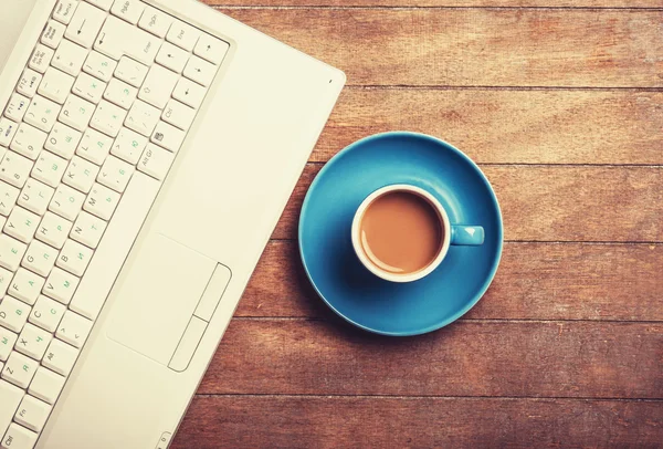 Tasse Kaffee und Laptop auf Holztisch. — Stockfoto