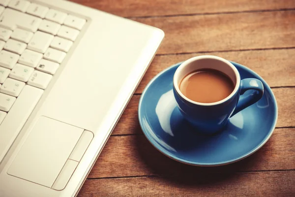 Kopp kaffe och laptop på träbord. — Stockfoto