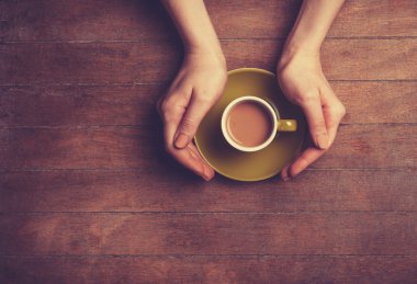 Kadın elleri bir fincan kahve tutuyor..