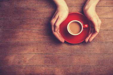 Kadın elleri bir fincan kahve tutuyor..