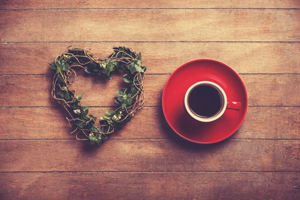 Kopje koffie en vorm hart op een houten tafel. — Stockfoto