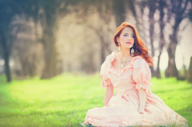 Bahar çimlerde oturan elbiseli güzel kadınlar.