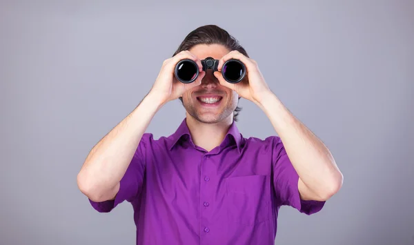Bonito homem com binocular no fundo cinza . — Fotografia de Stock