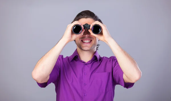 Schöner Mann mit Fernglas auf grauem Hintergrund. — Stockfoto