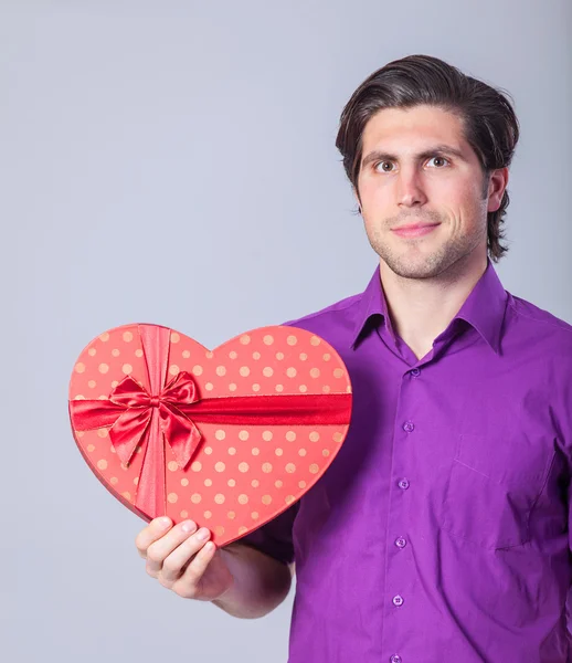 Handsome man with gift on gray background. — Stock Photo, Image