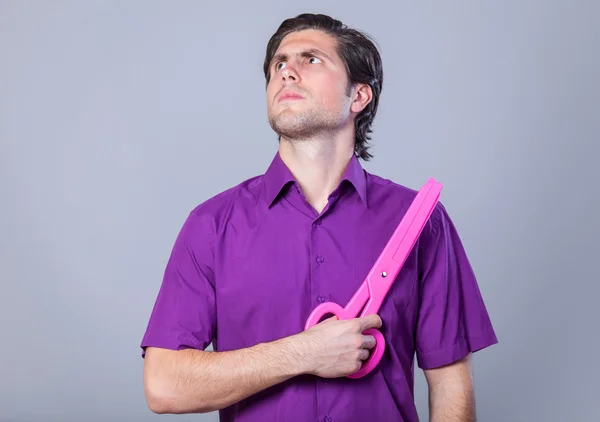 Man with huge scissors on gray background. — Stock Photo, Image