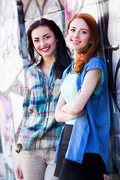 Two girls near graffiti wall. — Stock Photo, Image