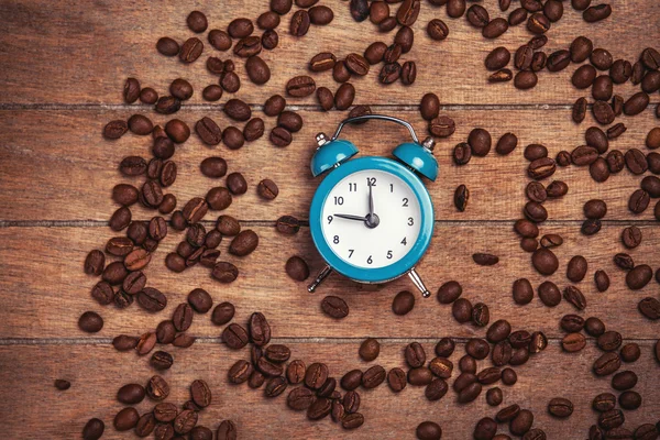 Alarm clock and coffee beans on a wooden table. — Stock Photo, Image