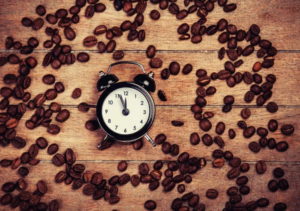 Väckarklocka och kaffebönor på ett träbord. — Stockfoto